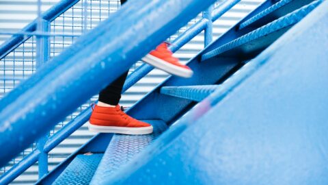 Person wearing orange sneakers walk up blue stairs